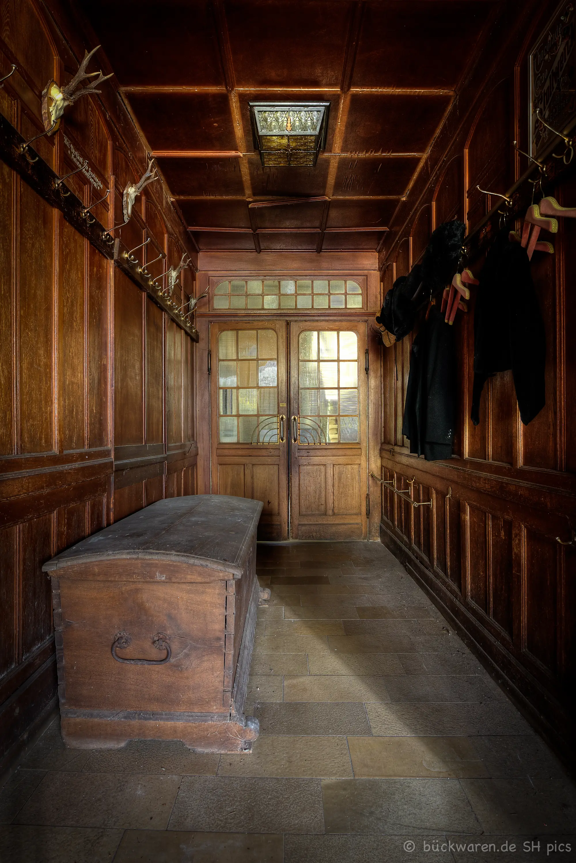 Garderobe mit Truhe. Die Mäntel hängen noch.