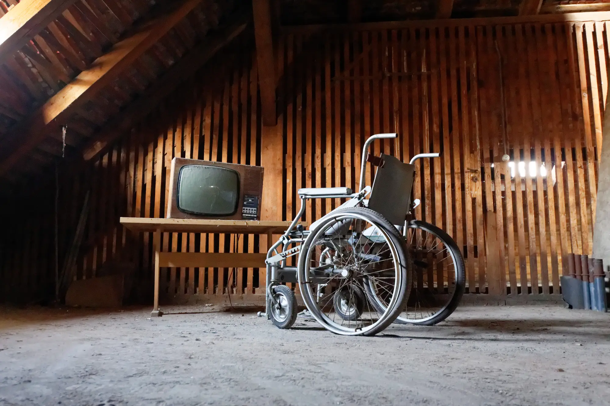 Auf dem Dachboden abgestellt: ein Fernseher und ein Rollstuhl.