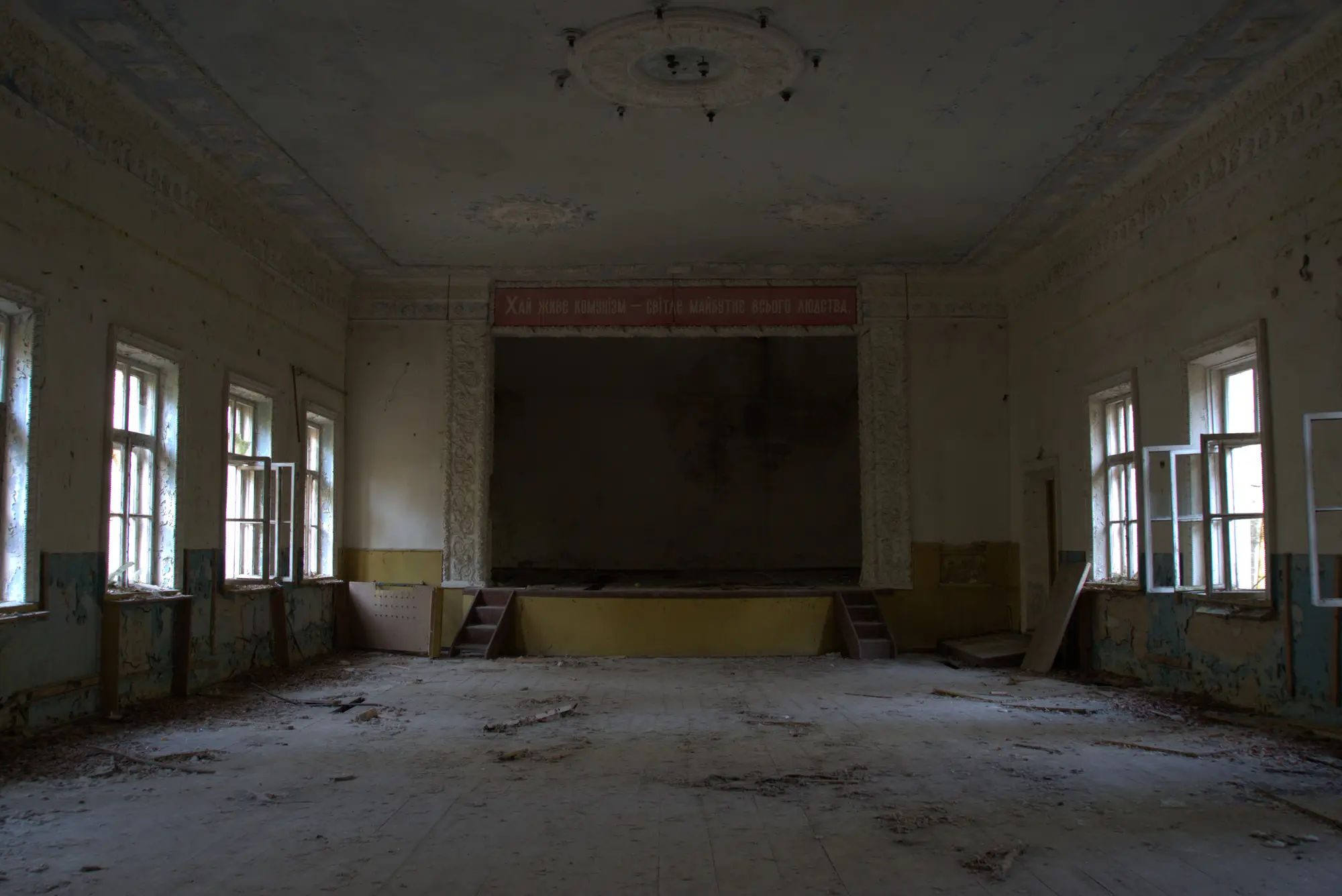 Der Saal. Über der Bühne hängt noch die Losung.
